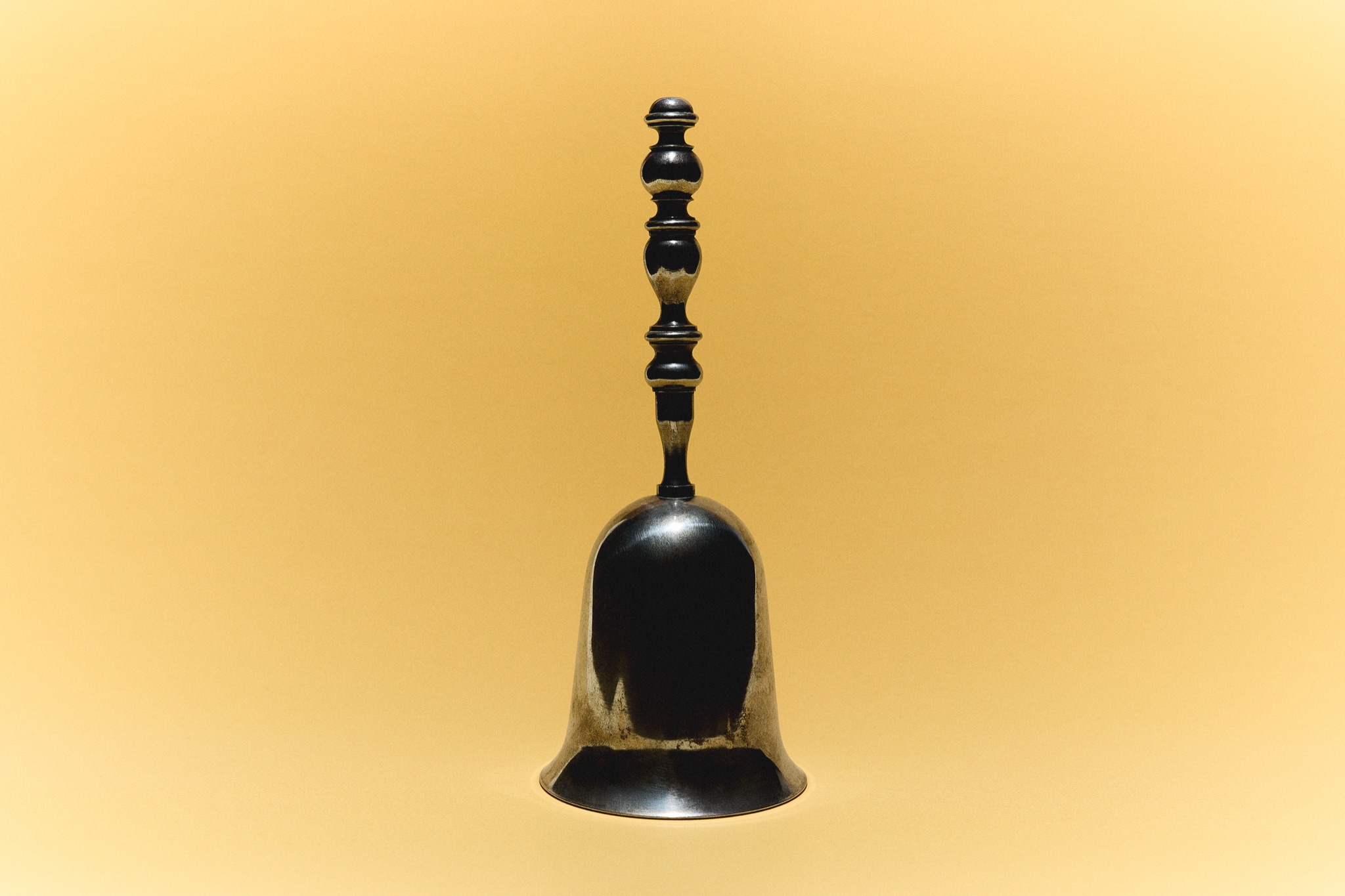 Antique black and gold hand bell on a golden background